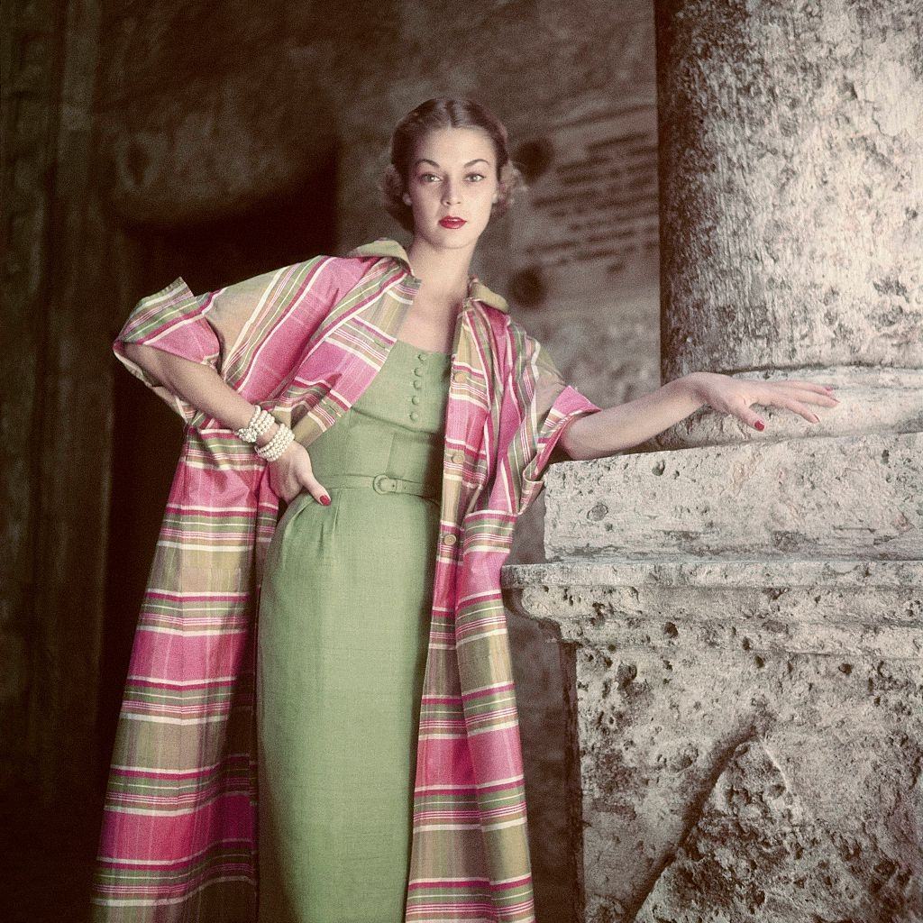 Jean Patchett wearing a sunsuit and standing against a striped background, 1951.