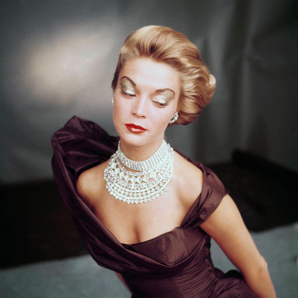 Jean Patchett wearing golden brown open neck satin evening dress with multi-strand rhinestone choker, 1951.