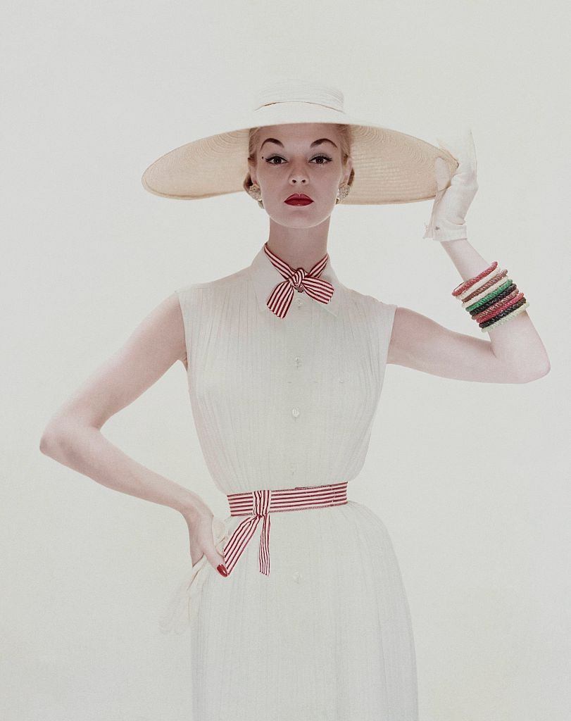 Jean Patchett wearing a white tucked crepe dress tied with red and white stripes, 1954.