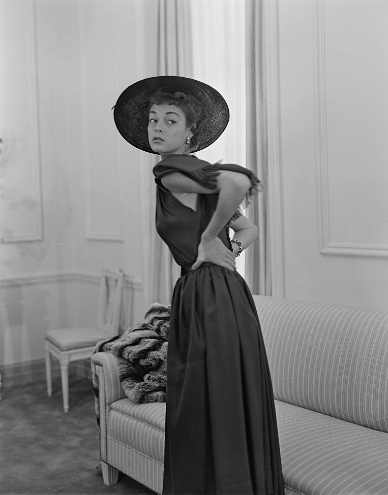 Jean Patchett wearing a Christian Dior dress with an attached scarf at the gathered neckline and a large hat. Vogue 1948.