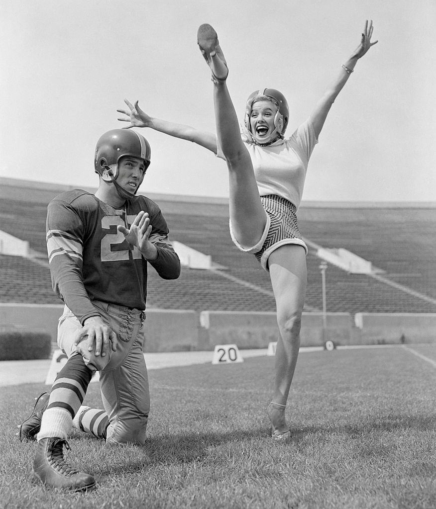 Mamie Van Doren Kicking on Football Field with Jim Sears, 1953.