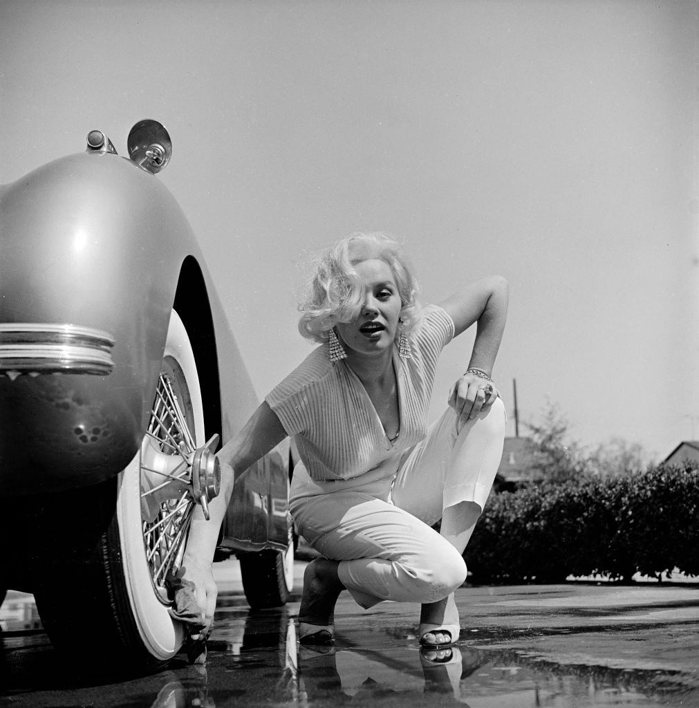 Mamie Van Doren washing the whitewall tires of her Jaguar, 1955.