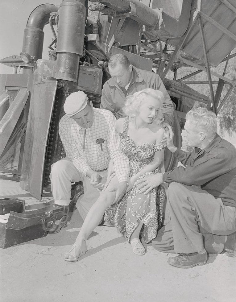 Mamie Van Doren Receiving Aid on Her Leg Injury, her leg was injured when caught in the spindles of a cotton picking machine on location near Bakersfield, 1957.