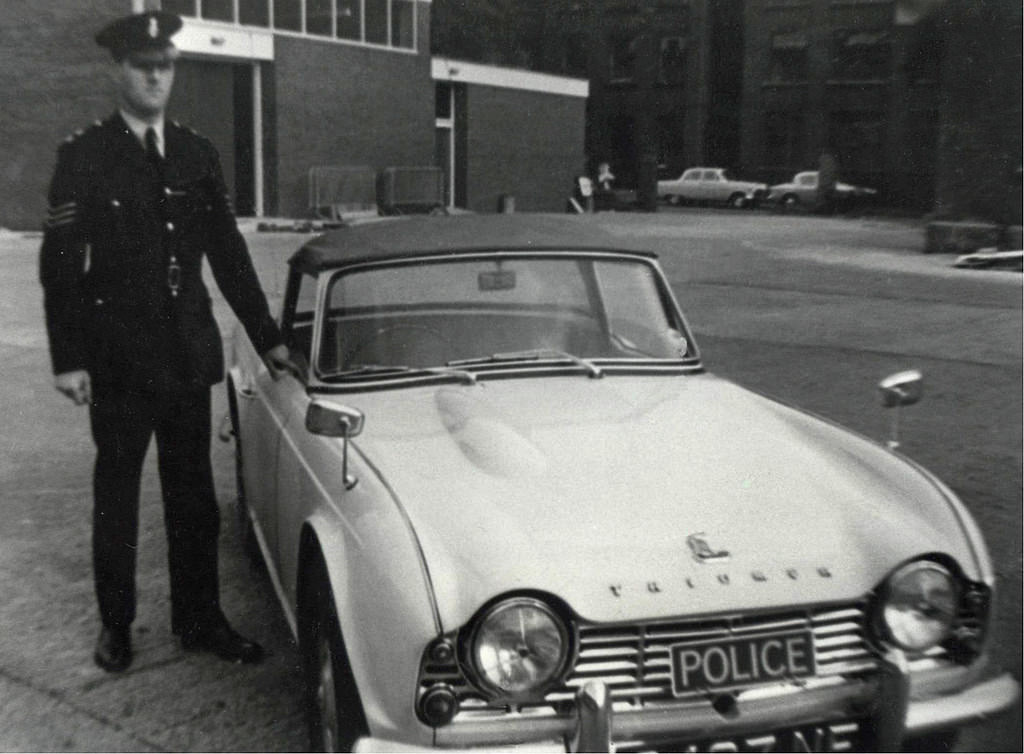 A Manchester City Police sergeant stands proudly alongside his Triumph TR4 patrol car in the yard of Longsight Police Station in the 1960s