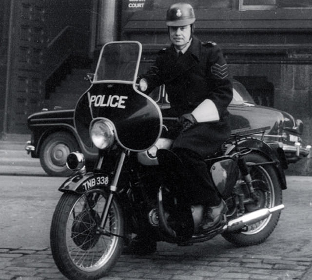A sergeant of Manchester City Police sits astride his police motorcycle outside Minshull Street Crown Court around 1960