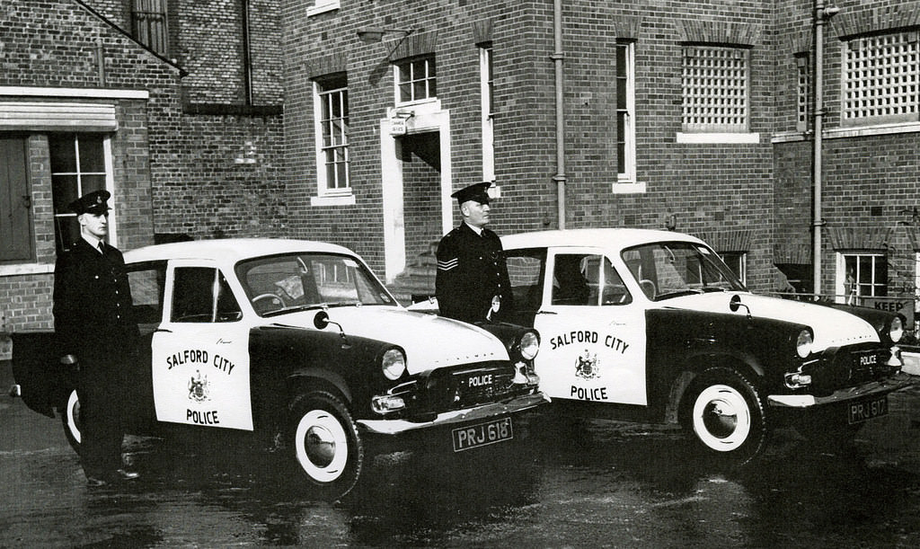 Salford City Police officers proudly display their Hillman Minx patrol cars in the rear yard of their headquarters building in central Salford around 1960.