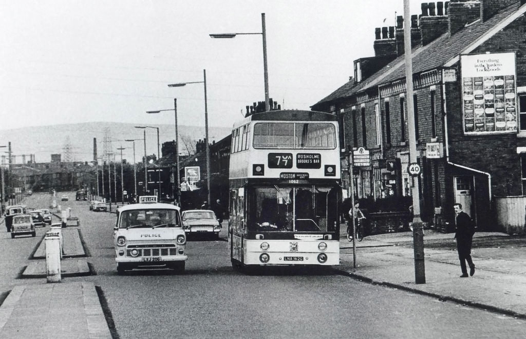 A Ford Transit police van overtaking a number 77 bus on a North Manchester road in the early 1970s