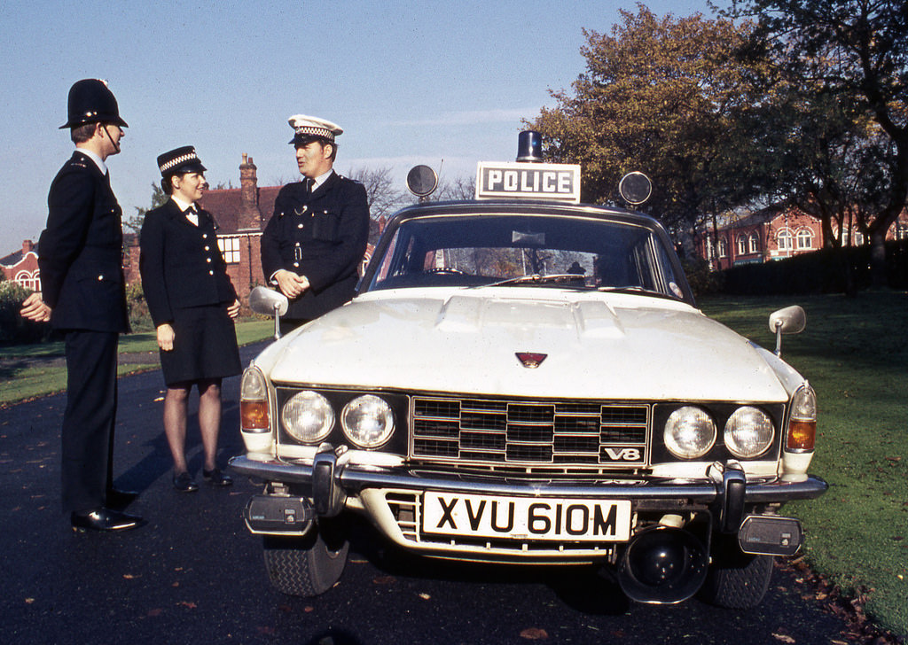 A traffic officer stands beside his Rover P6 V8 vehicle as he chats to colleagues out on foot patrol, 1973