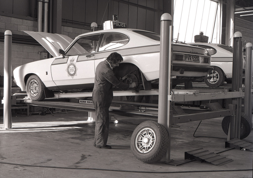 A mechanic works on a Greater Manchester Police Ford Capri in the Force's vehicle workshop in Openshaw, 1978