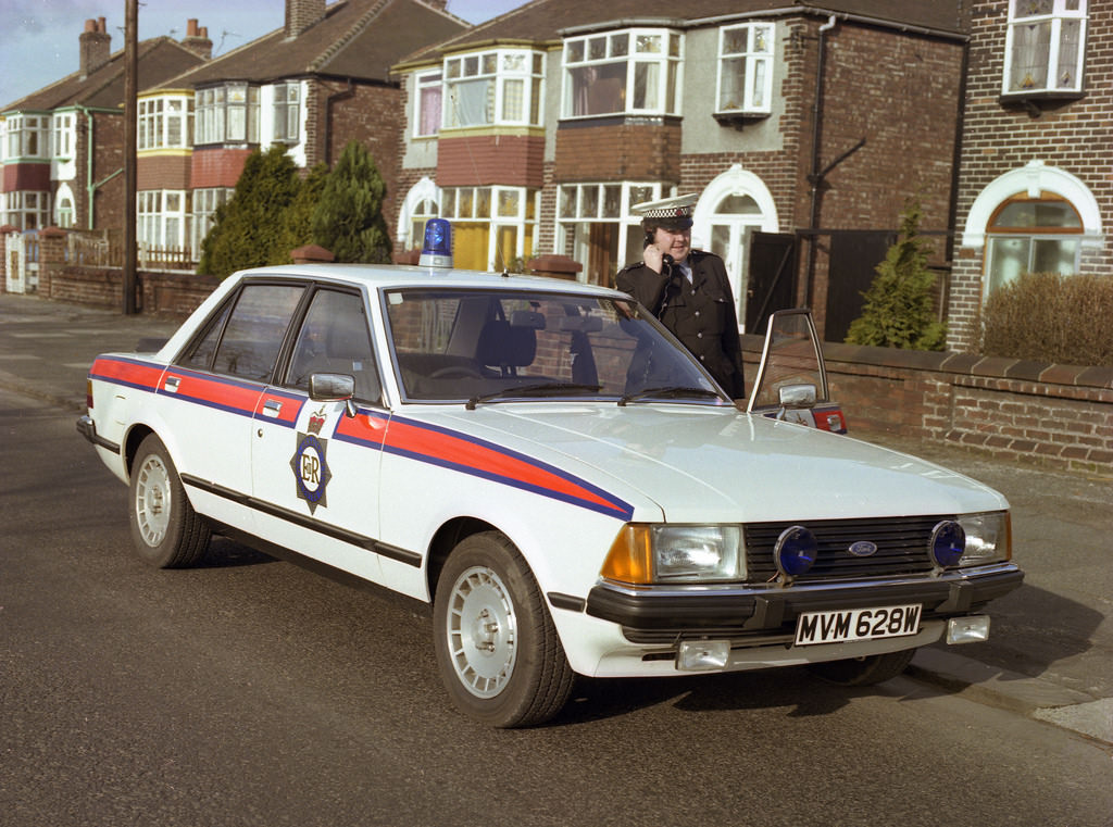 A Greater Manchester Police traffic officer poses with his Ford Granada in the early 1980s