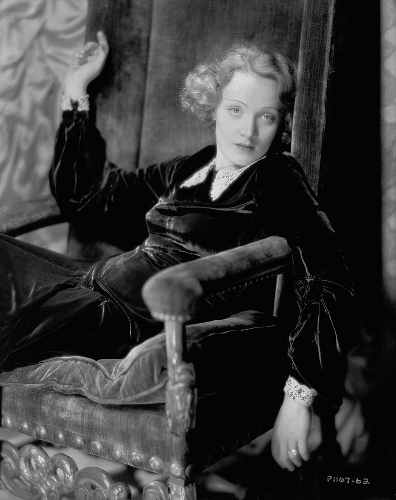 Marlene Dietrich slumped into a velvet chair, 1930.