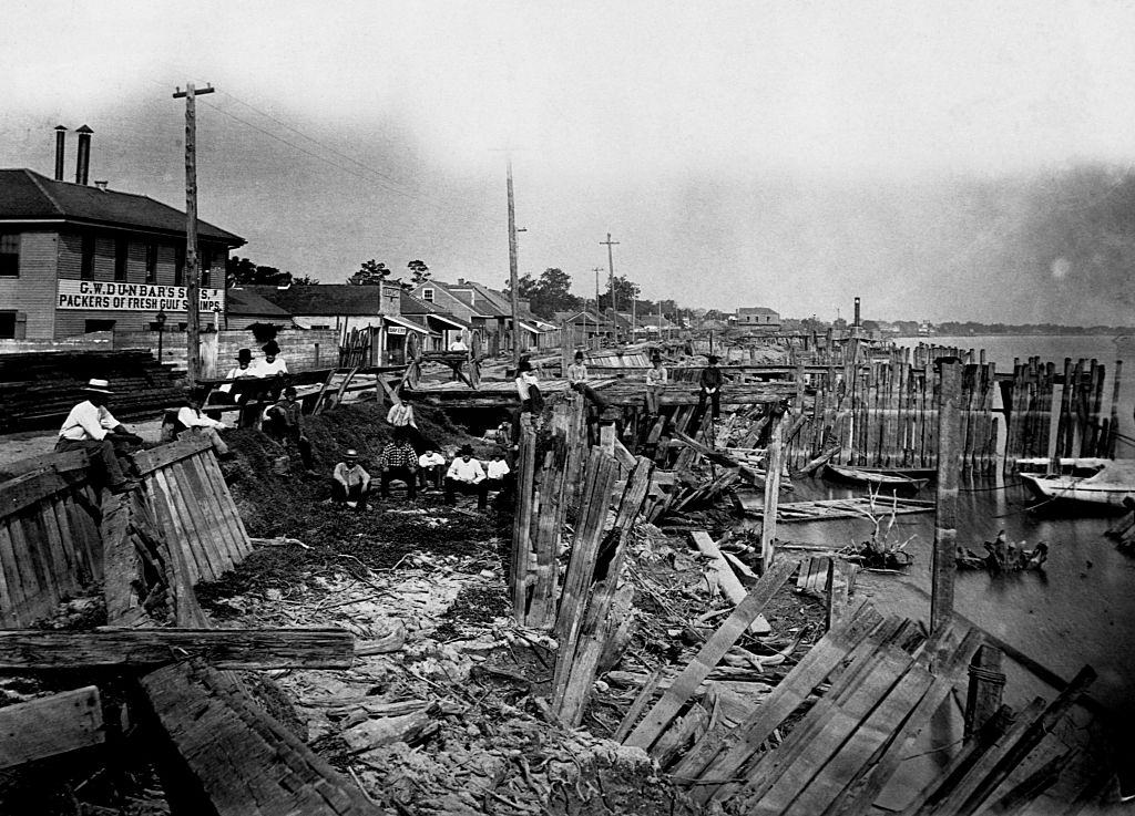 A group of men sit on weather-beaten wharves between Piety and Desire Streets, New Orleans, August 1881.