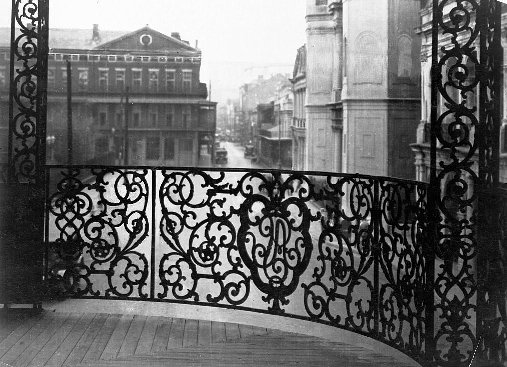 An elaborate metal filigree railing adorns the second story of this historical building overlooking the street in New Orleans, 1899.