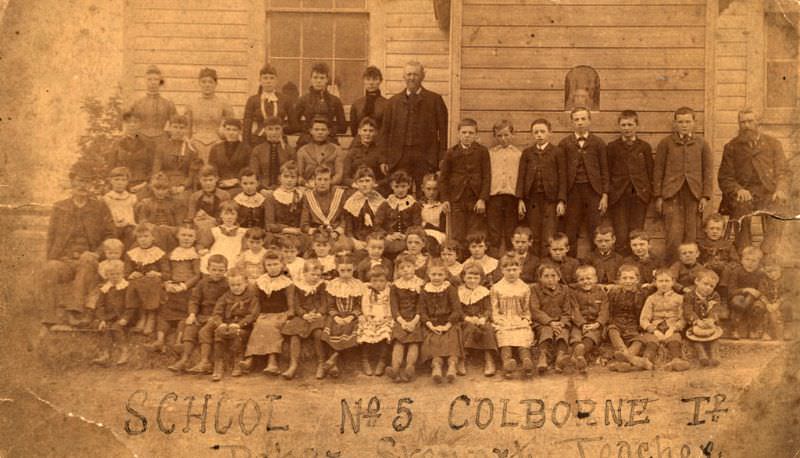 Students and teachers in front of frame building, Colborne, Ontario, 1880s.