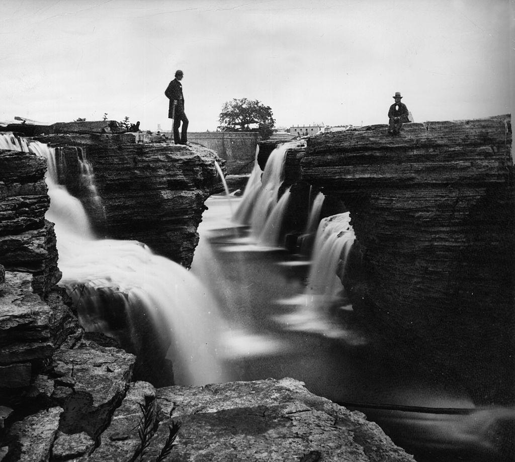 Gentlemen contemplate the beauty of the Chaudiere falls on the River Ottawa, 1860.