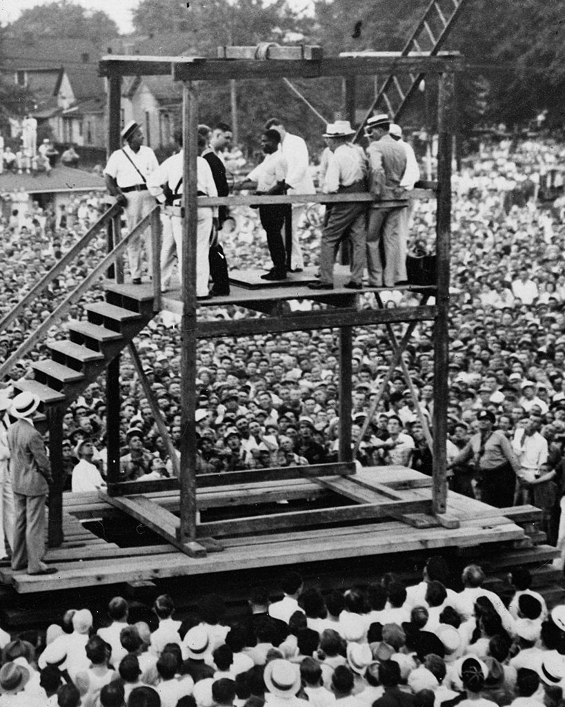 Rainey Bethea listens attentively to the prayers of a priest as the hangman makes final adjustments on the noose.