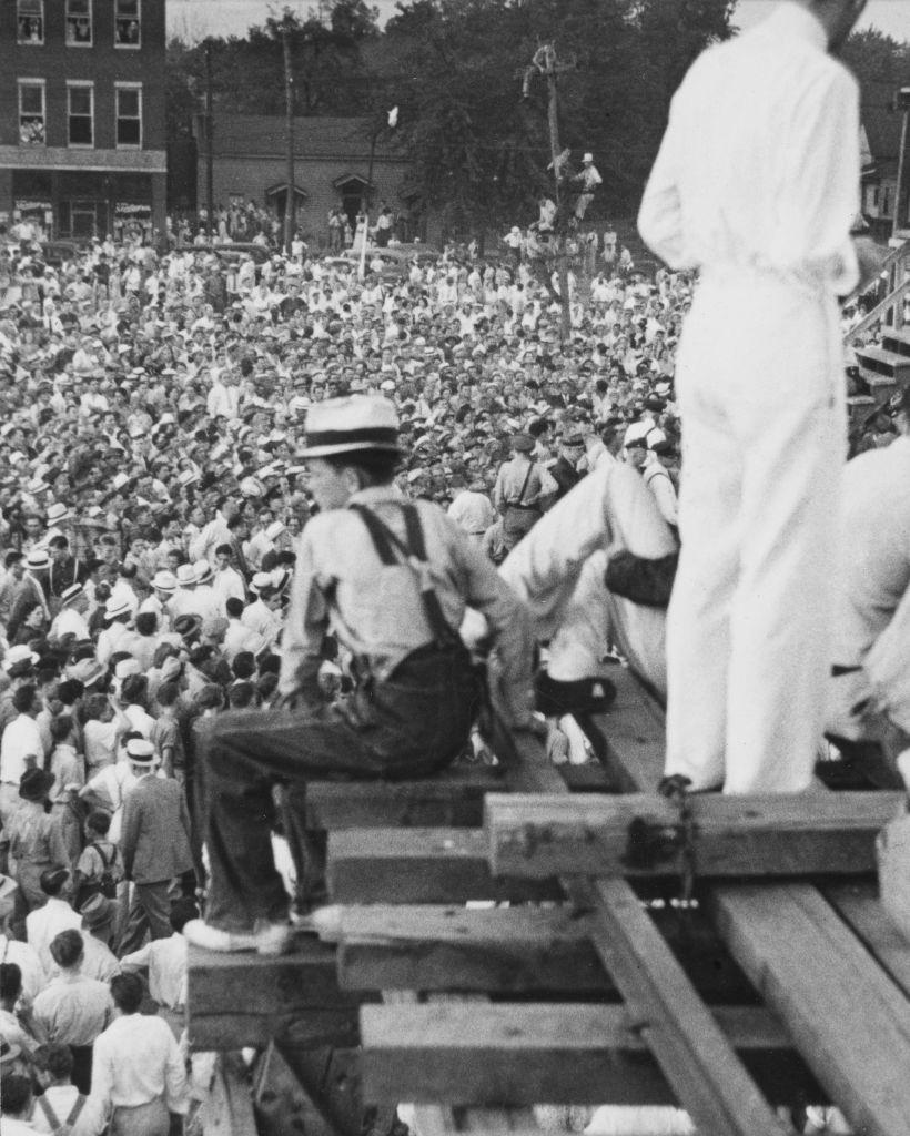 A figure sits on wood-built structure looking across the crowd of approximately 20,000 people who had gathered to witness the public hanging of Rainey Bethea in Owensboro, Kentucky.