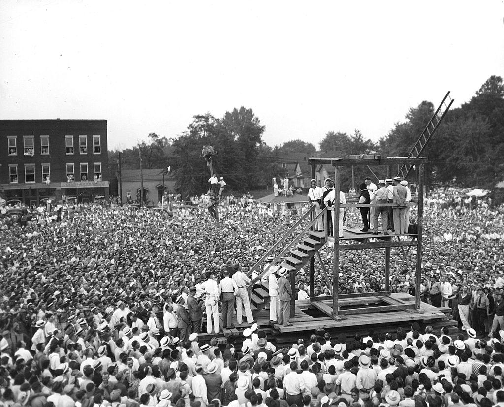 A huge crowd of people gathers around a scaffold to witness the public hanging of 26-year old Rainey Bethea.