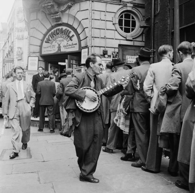 A banjo player entertaining the customers outside the Windmill Theatre, 1953.