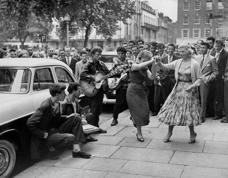 A group playing and jiving in the street at a fair, 1957.