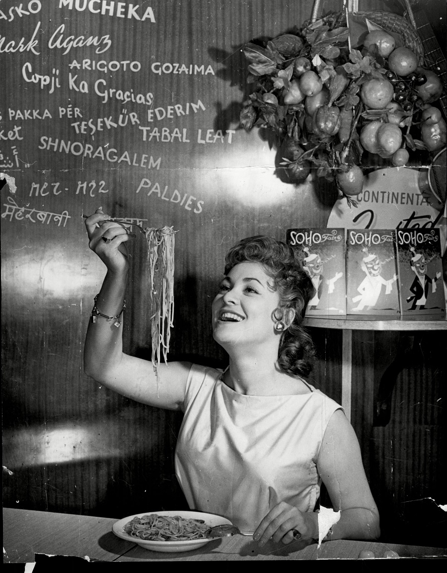 Soho’s Fair Queen Andria Loran (real Name Maureen Smith) tries her skill at Spaghetti Eating, July 1956.