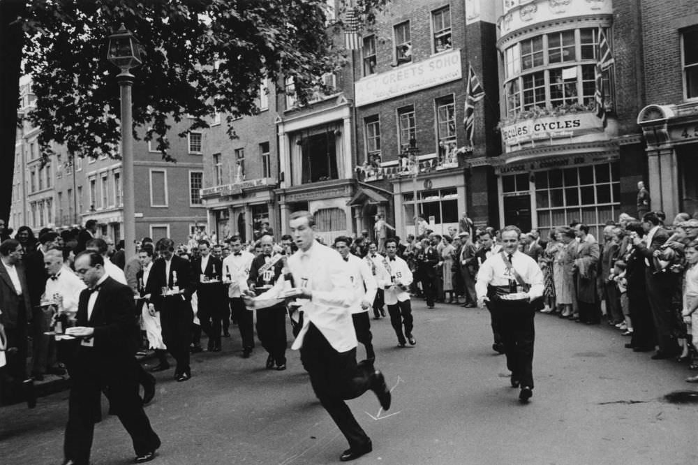 Waiters carrying half bottles of champagne set off on the annual waiters’ race from Soho Square to Greek Street in 1955.