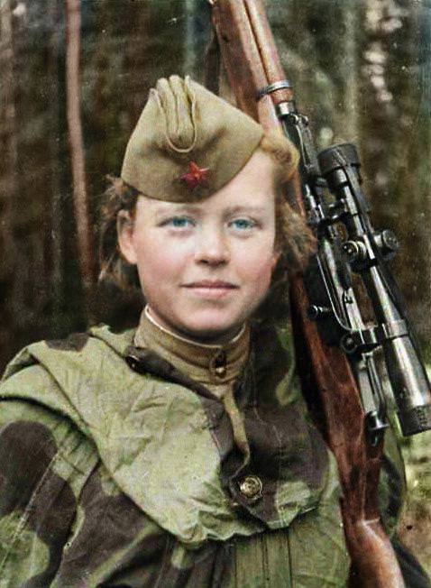 Sniper volunteer Nadezhda Kolesnikova is pictured smiling alongside her weapon.