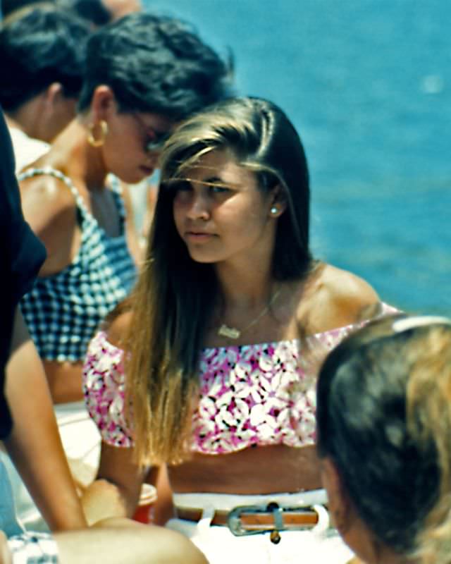 Girl was sitting by the waterfront during the annual festival in West Palm Beach in the midst of the crowds, 1990