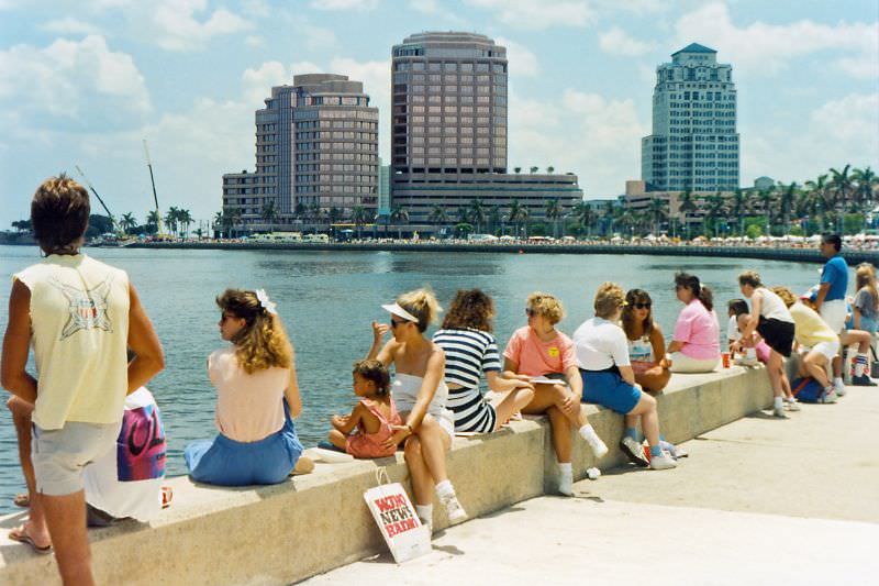 People take a break at the Lake Worth seawall during F, with Phillips Point buildings in the background, 1990