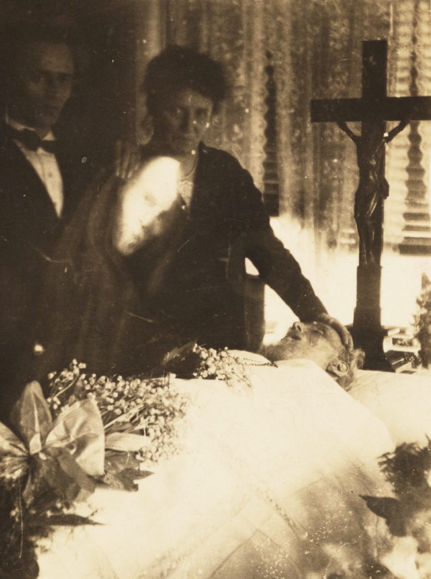 A man's face appears over a funeral scene.