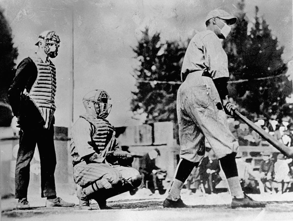 Unident baseball players, one batting & one catching, with umpire standing behind plate, wearing masks which they thought would keep them from getting flu during influenza epidemic of 1918.