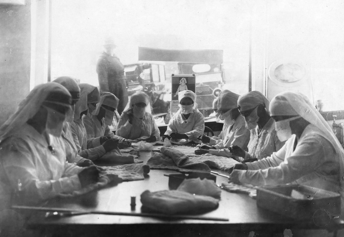 Combatting influenza in Seattle in 1918. At work in the Red Cross rooms in Seattle, Washington, with influenza masks on faces.