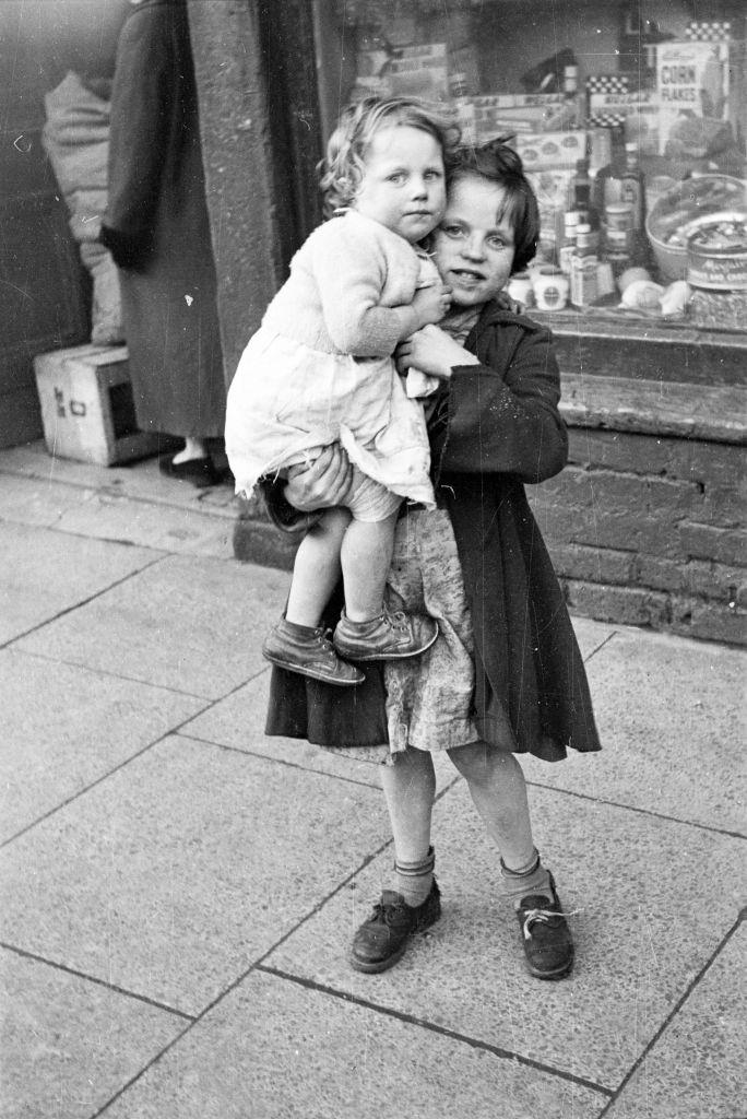 A little girl looking after her younger sister on a street in Belfast, 1954.