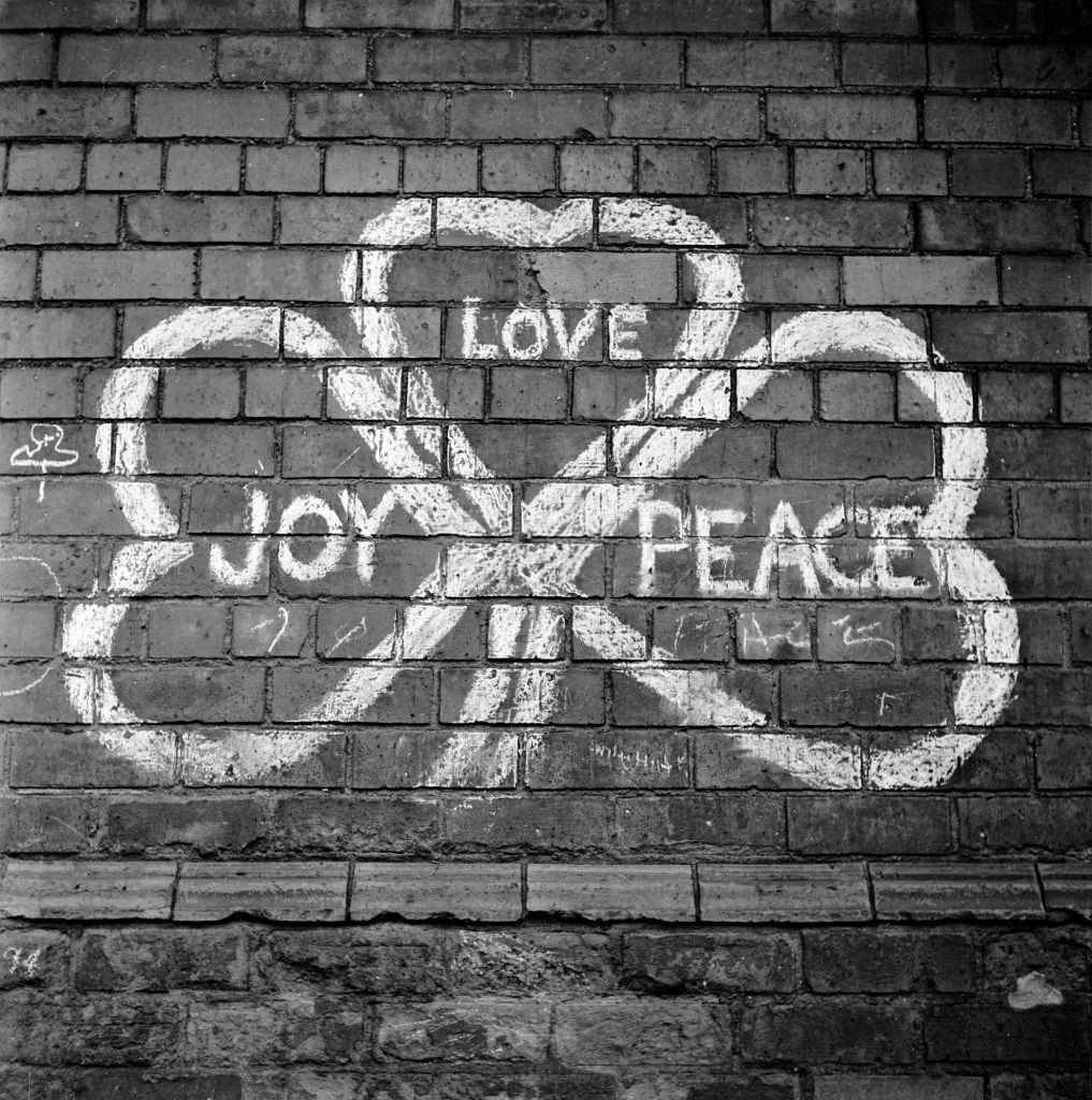 A painted sign on a wall in Belfast reading 'Joy, Love, Peace' in the shape of a shamrock, 1954.