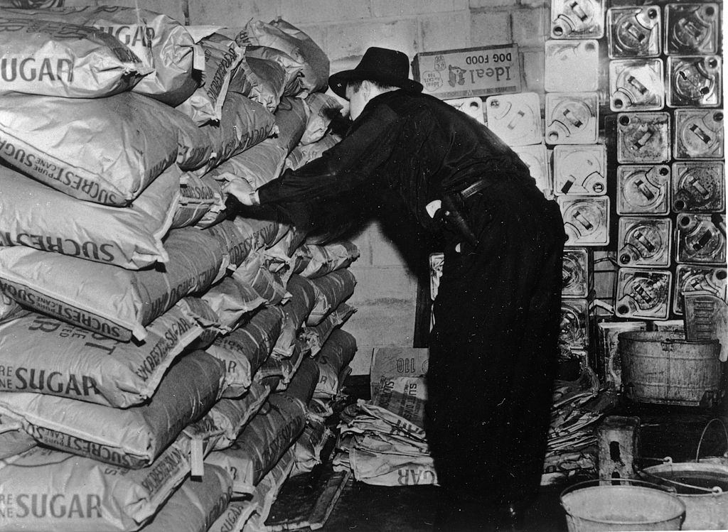 An American Revenue agent inspects 200 bags of sugar found in a Brooklyn warehouse which was capable of producing 2,500 gallons of illegal liqour a day, 1950.