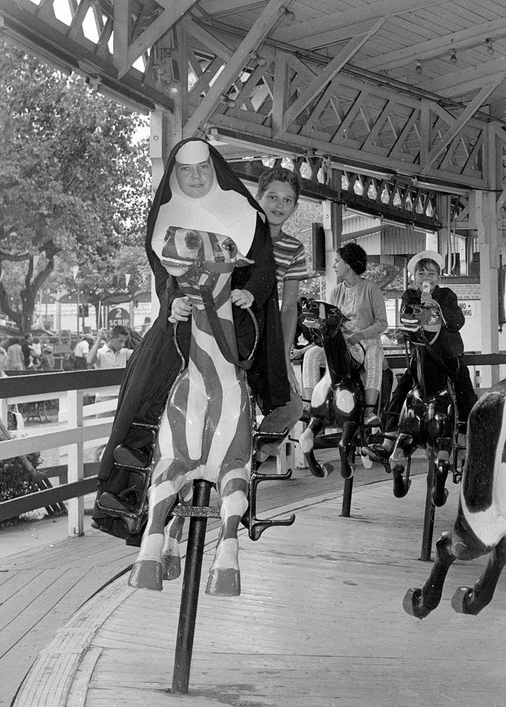 A Roman Catholic nun and a young boy enjoy a carnival ride at a church picnic in Brooklyn, New York City, 1955.