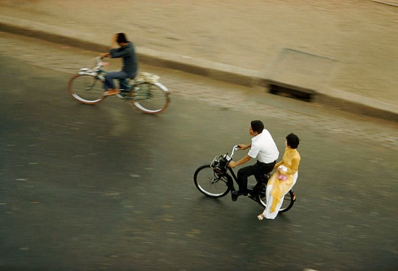 A man and a traditionally dressed woman speed by on a motorbike in Saigon, 1961