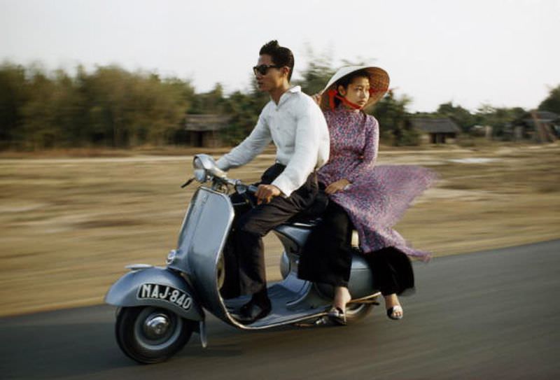 A nattily dressed young couple zip down the road on a motor scooter in Saigon, 1961