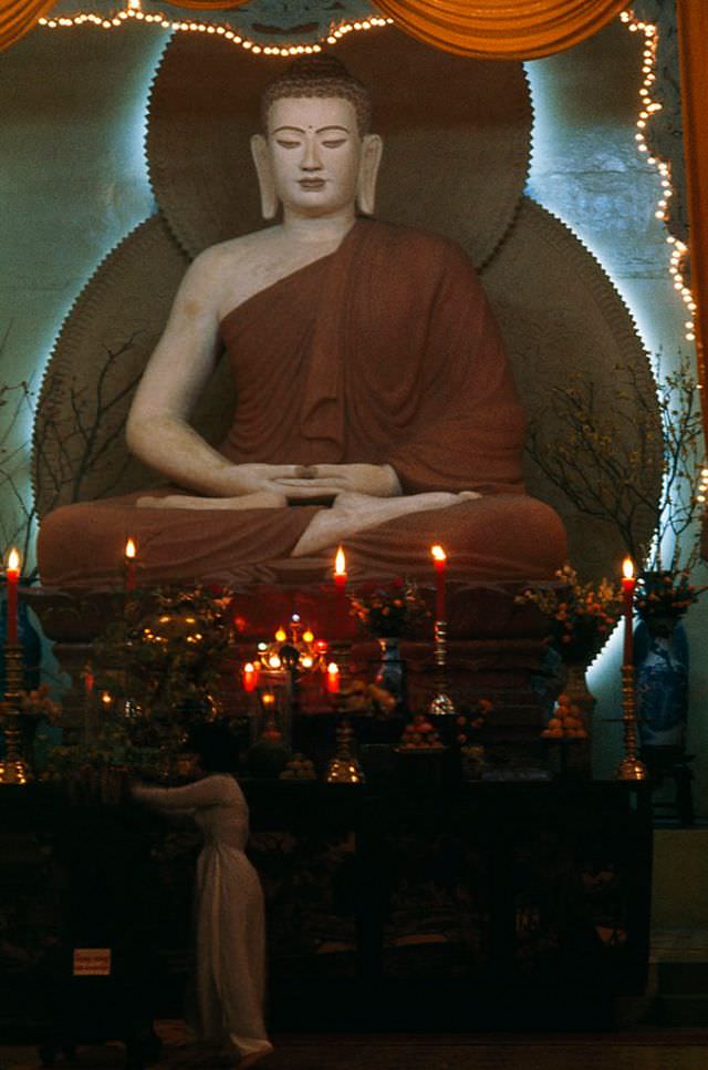 A woman approaches an altar barefoot, as custom demands in Saigon, 1965