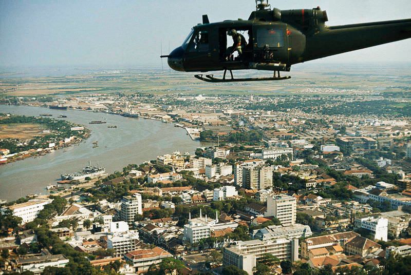 An armed Bell UH-1B helicopter flies over Saigon, 1965