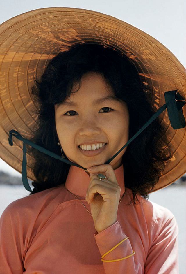 An umbrellalike poetry inscribed ‘non la’, or hat, shades a girl's face in Saigon, 1961