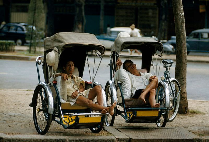 Tired cyclo drivers stretch out for siestas in their cabs in Saigon, 1961