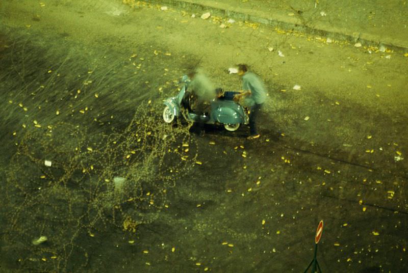 Two men struggle to free their scooter from a barbed-wire barricade in Saigon, 1965