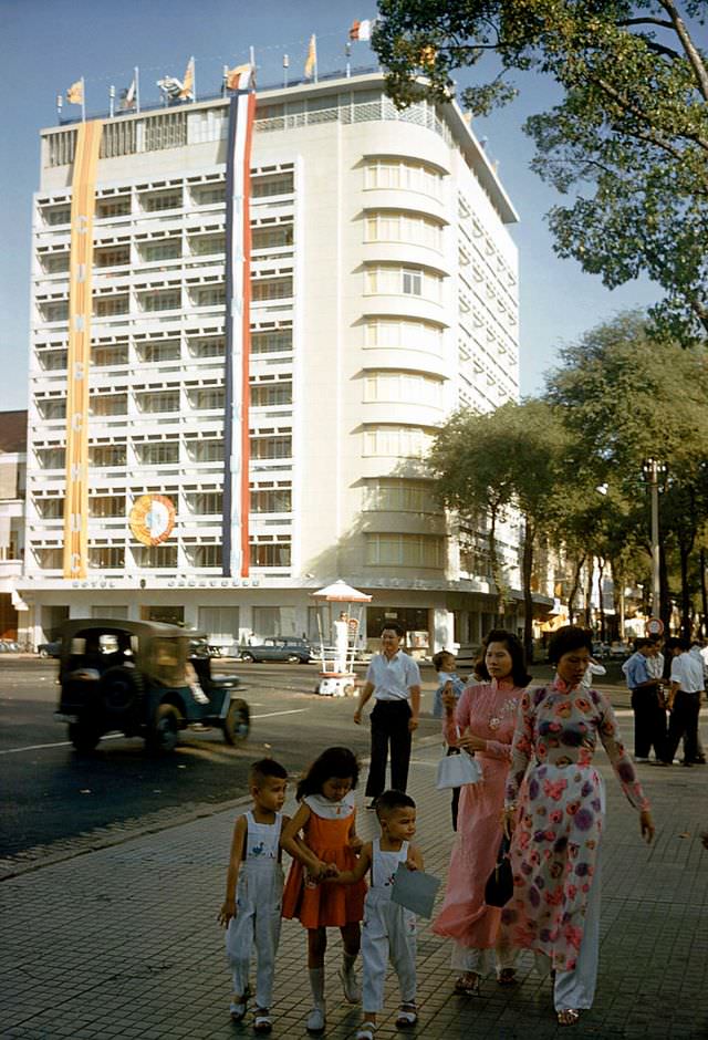 Women dressed in ‘Ao Dai’ stroll down the street with their children in Saigon, 1961