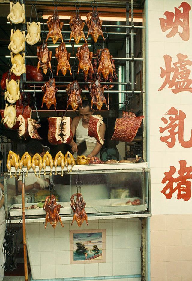 A butcher works behind an array of raw and cooked meat and poultry in Saigon, 1965