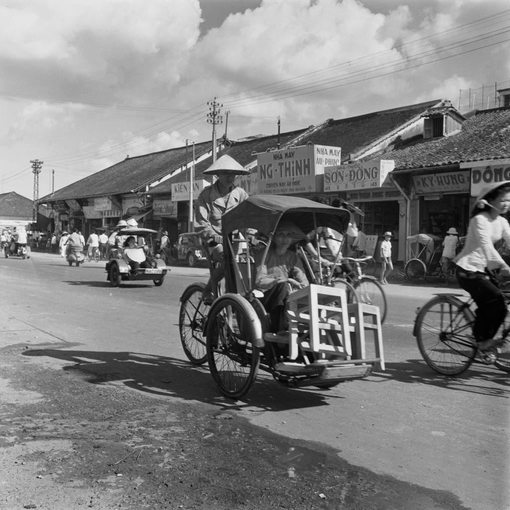 A woman carrying stools home on a bicycle rickshaw in Saigon, 1962.