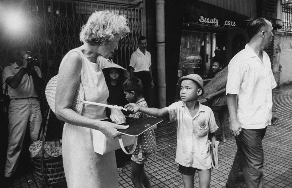 Mrs. Henry Cabot Lodge, wife of US Amb., giving money to a boy, 1963.