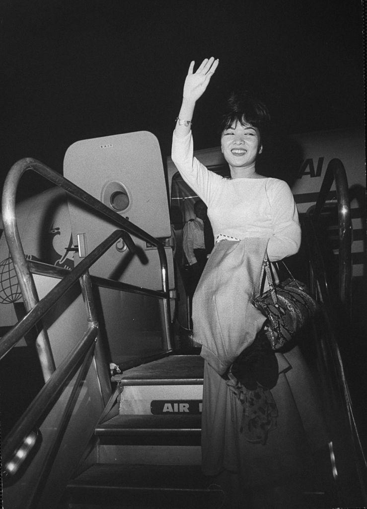 Madame Ngo Dinh Nhu waving from the stairs of an airplane, 1963.