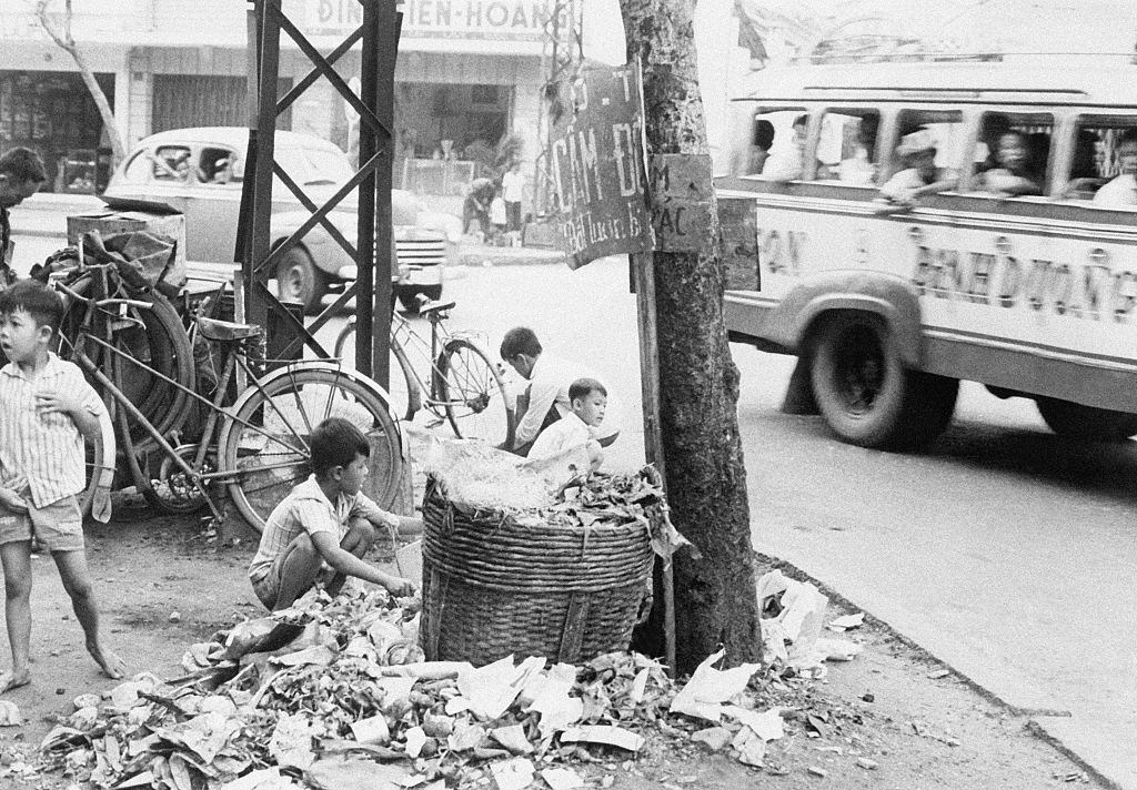 Young Vietnamese children search a garbage dump to try to find something to sell or eat, July 30, 1965