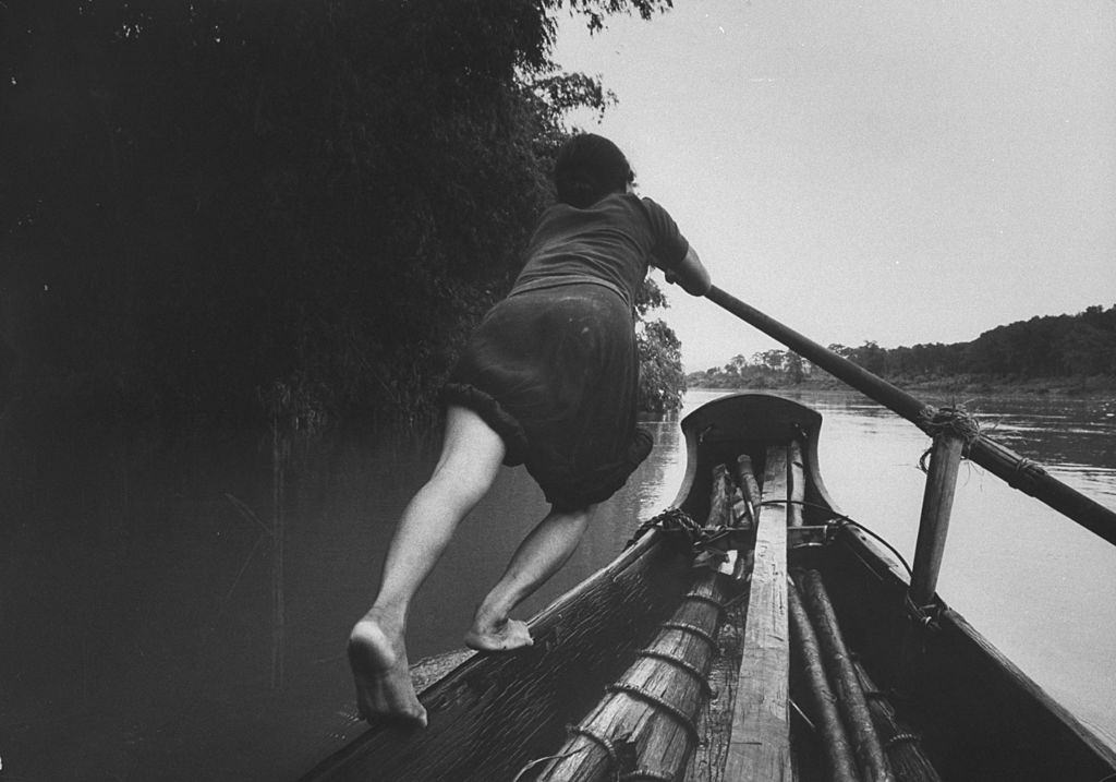 Boat girl rowing passenger-carrying sampan across Perfume River, 1961.